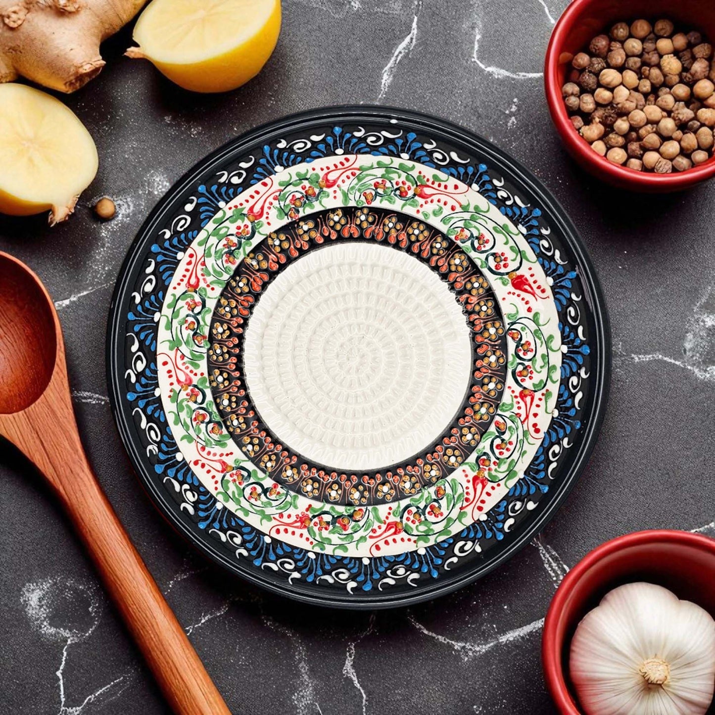 Decorative garlic grater bowl with intricate patterns on a dark surface with kitchen items.