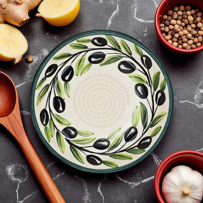 Decorative ceramic garlic grater bowl with olive design on a kitchen counter with ingredients.