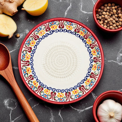 Decorative garlic grater bowl with colorful on a dark surface with kitchen items.