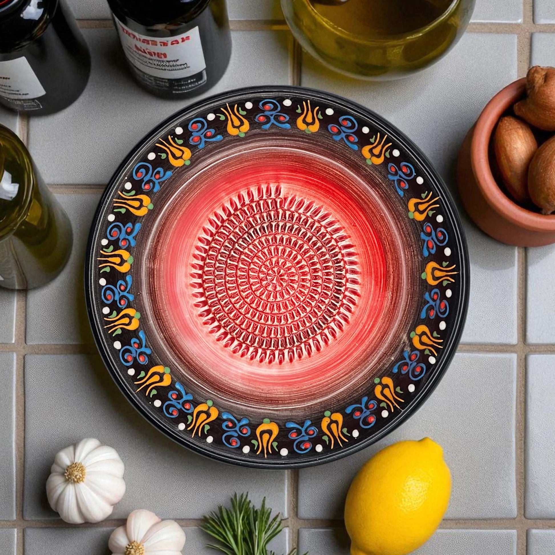 Decorative ceramic garlic grater bowl with colorful patterns on a tiled surface with ingredients.
