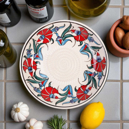 Decorative ceramic garlic grater bowl with floral design on a tiled surface with lemons and herbs.