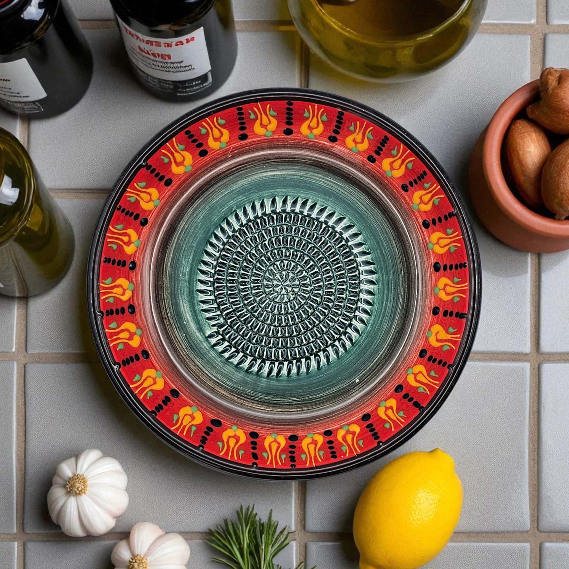 Decorative ceramic garlic grater bowl with colorful on a tiled surface with lemons and herbs.