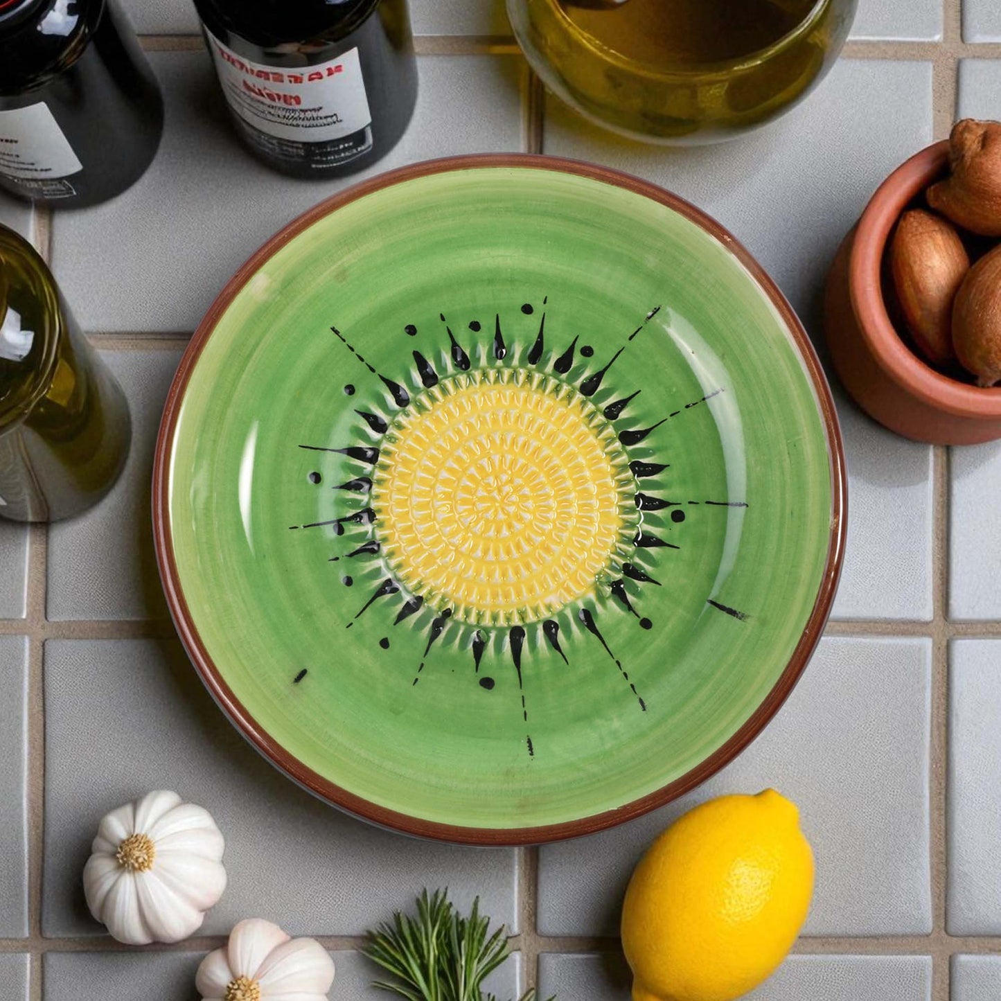 Green ceramic garlic grater bowl with yellow center on a tiled surface with ingredients