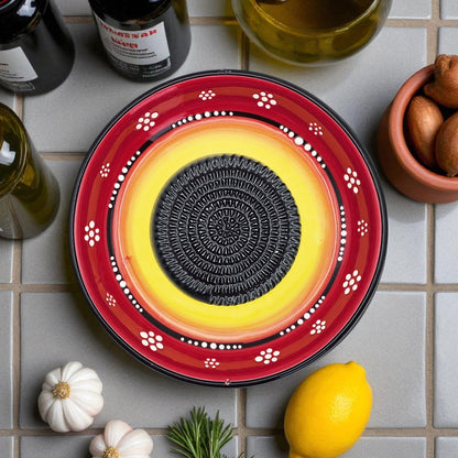 Decorative garlic grater bowl with concentric circles on a tiled surface with ingredients.