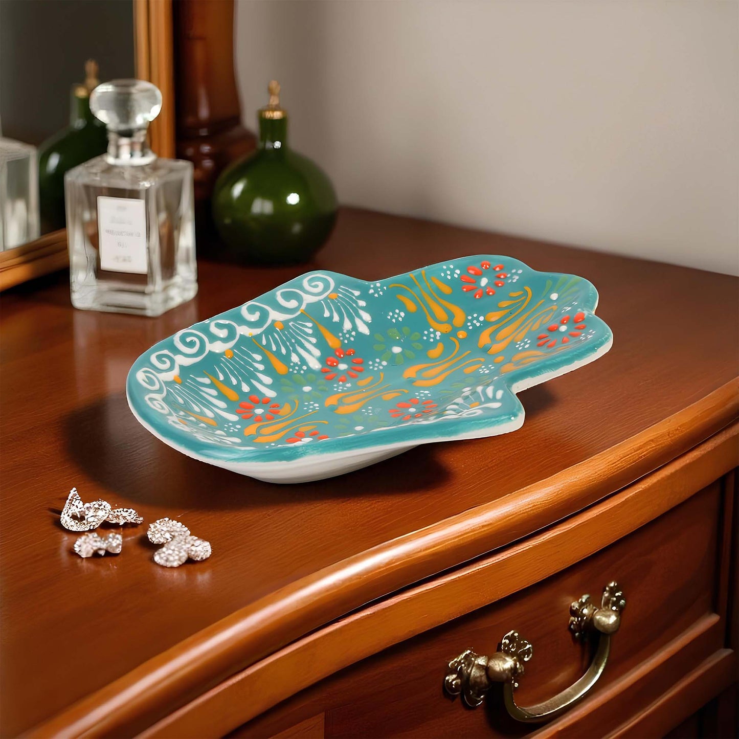 Decorative turquoise jewelry tray with colorful patterns on a wooden surface