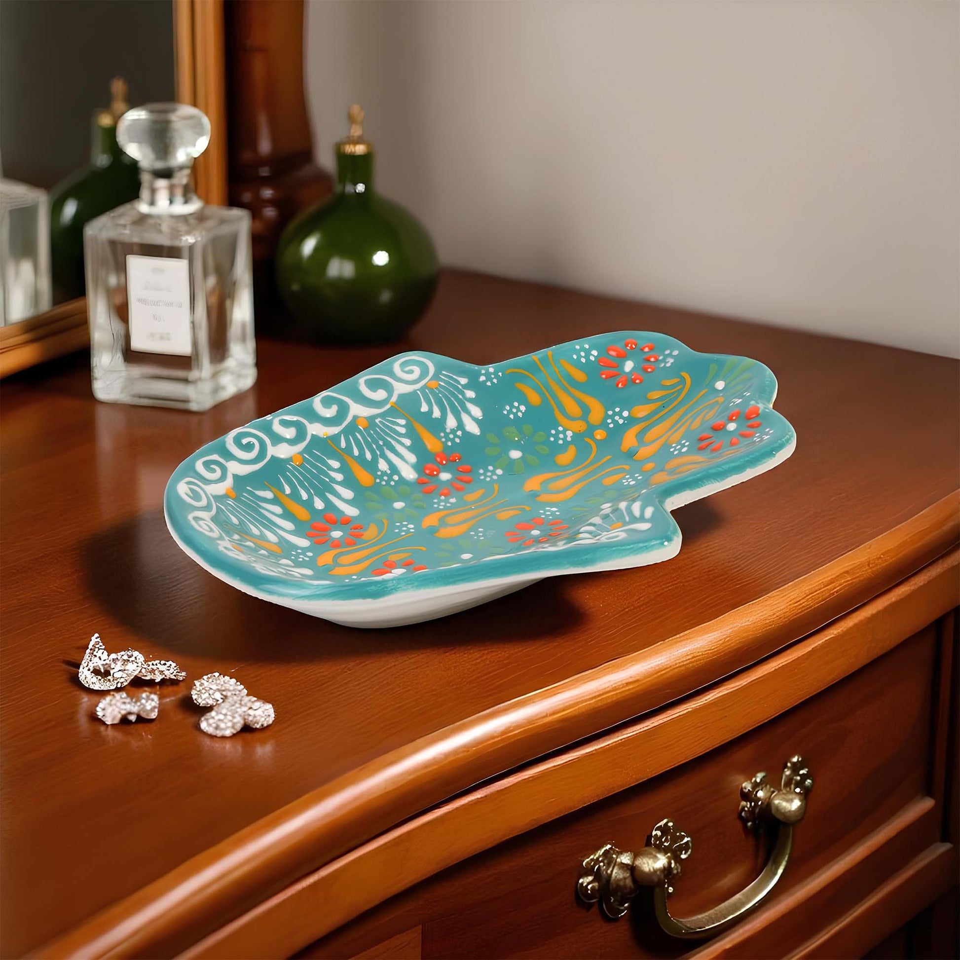 Decorative turquoise jewelry tray with colorful patterns on a wooden surface
