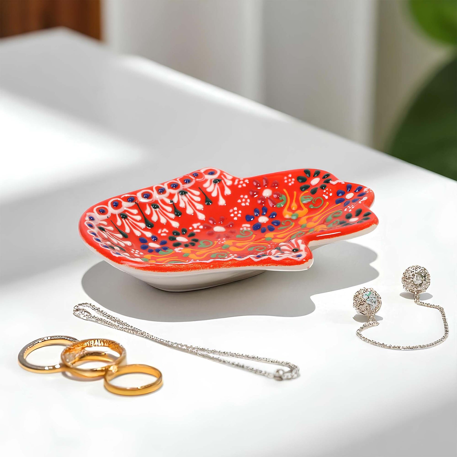 Decorative red jewelry tray with jewelry on a white surface