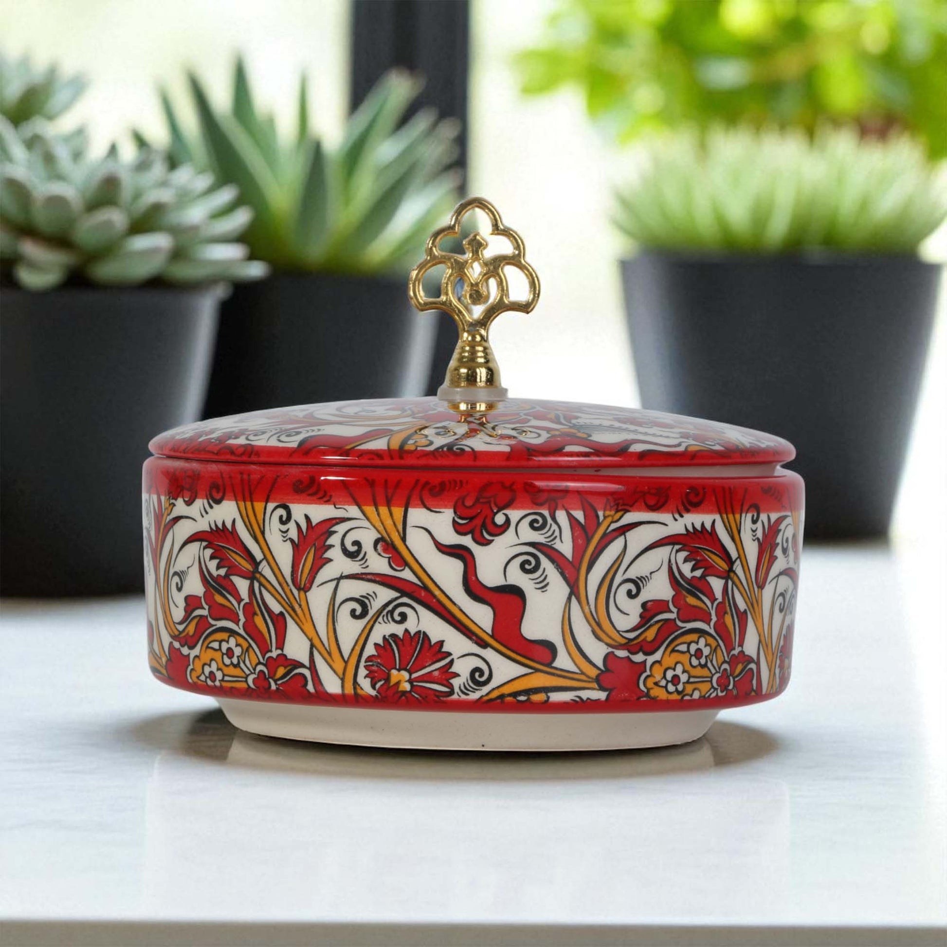 Decorative ceramic sugar bowl with floral patterns on a white surface with plants in the background