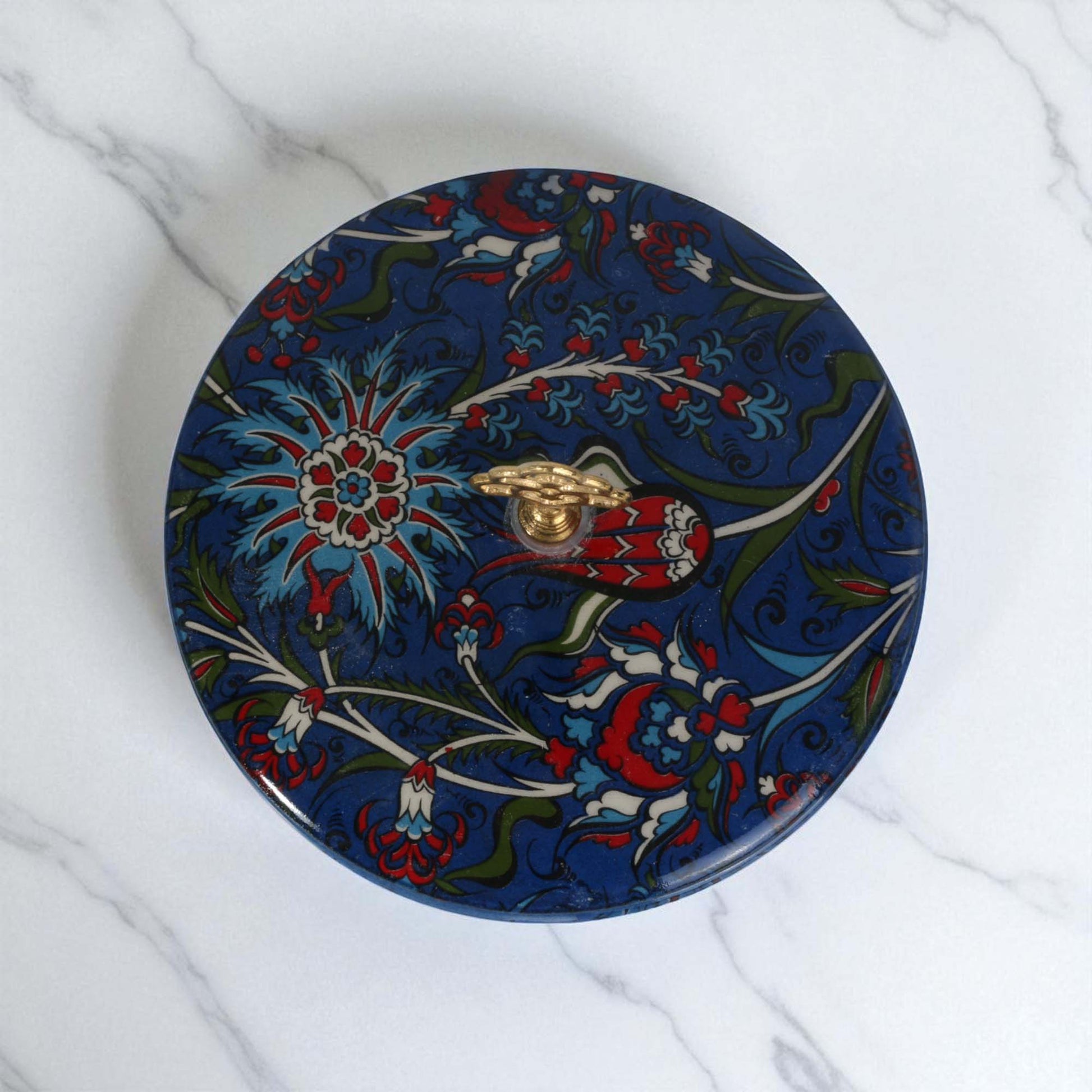 Decorative round sugar bowl with floral patterns on a marble surface