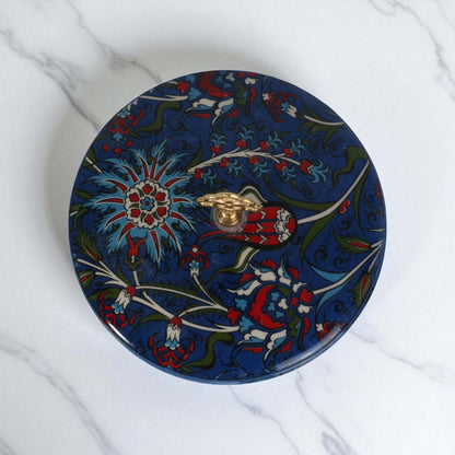 Decorative round sugar bowl with floral patterns on a marble surface