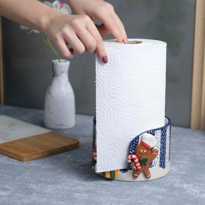 Person using a paper towel with a decorative paper towel holder featuring a gingerbread man design.