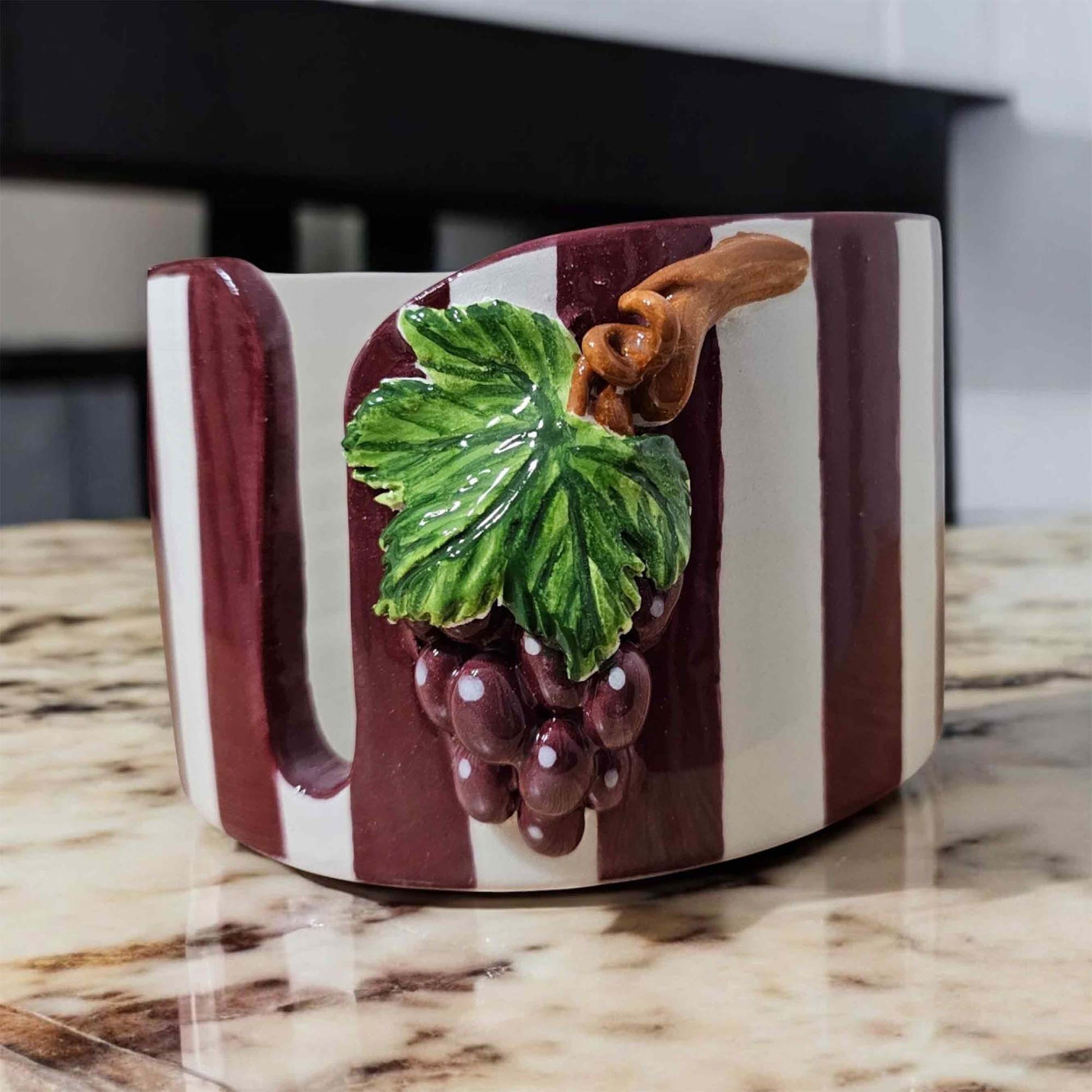 Decorative paper towel holder with grape design on a marble surface