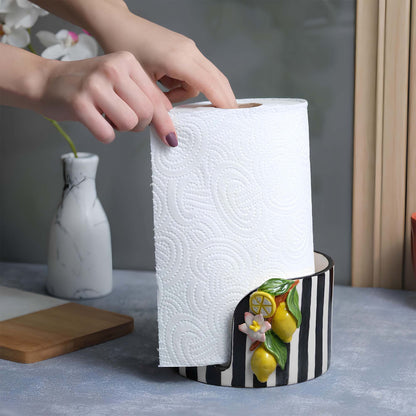 Person retrieving paper towels from a decorative paper towel holder on a kitchen counter.