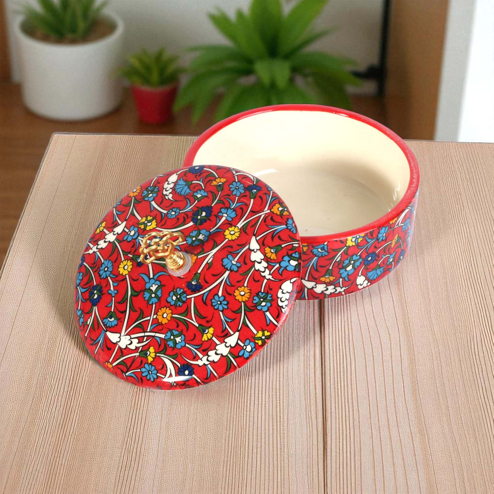 Decorative red sugar bowl with floral pattern on a wooden surface