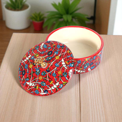 Decorative red sugar bowl with floral pattern on a wooden surface