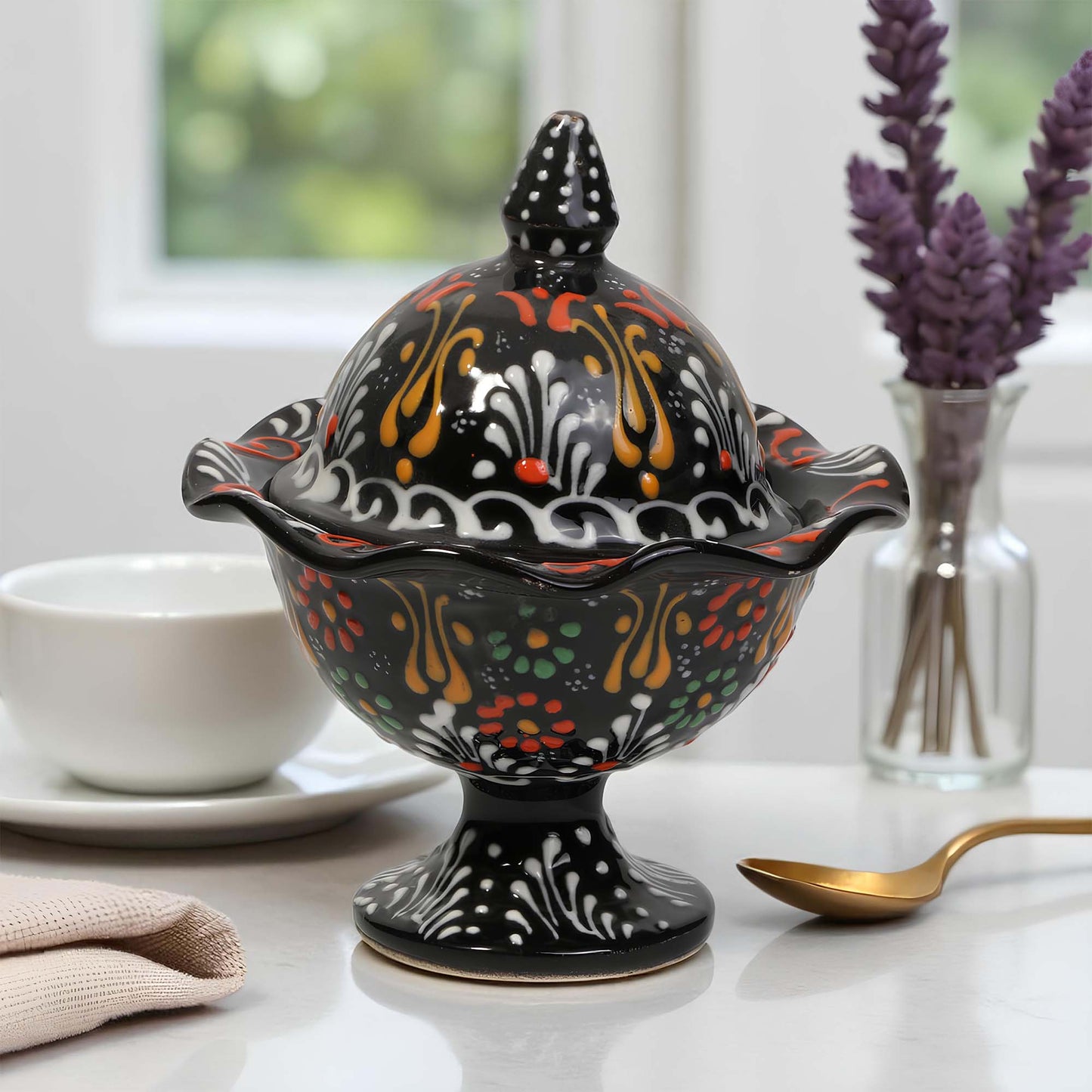 Decorative ceramic sugar bowl with colorful patterns on a table with a spoon and lavender.