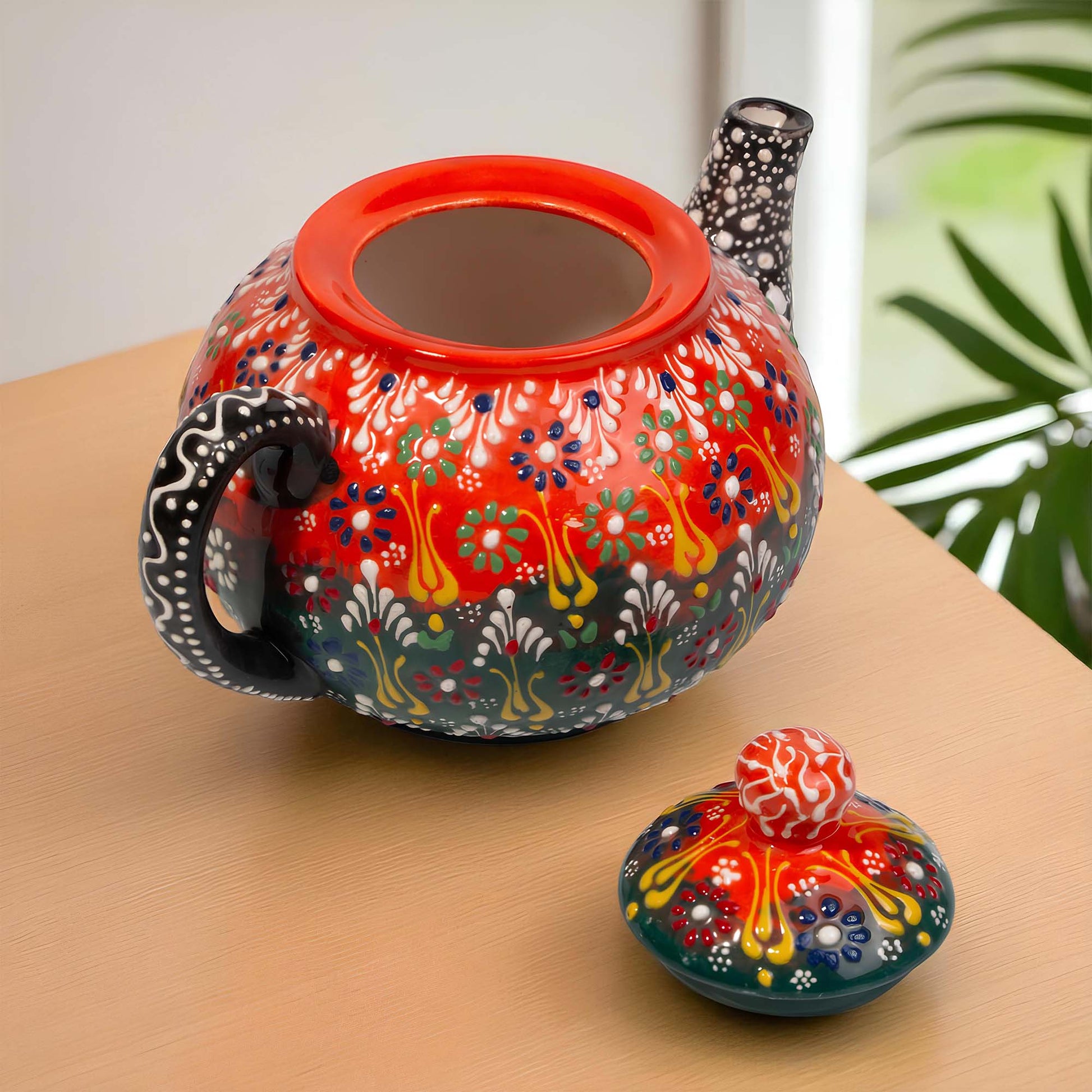 Colorful ceramic teapot with intricate patterns on a wooden surface.