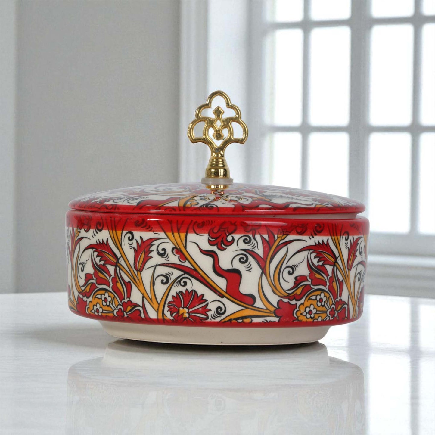 Decorative ceramic sugar bowl with floral patterns and a gold lid on a white surface.