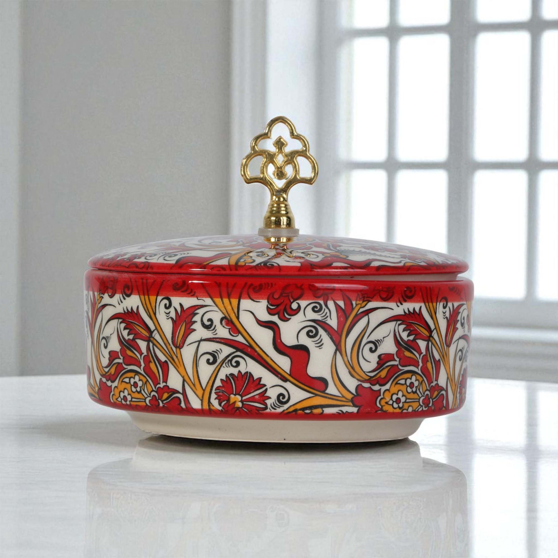 Decorative ceramic sugar bowl with floral patterns and a gold lid on a white surface.