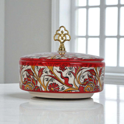 Decorative ceramic sugar bowl with floral patterns and a gold lid on a white surface.