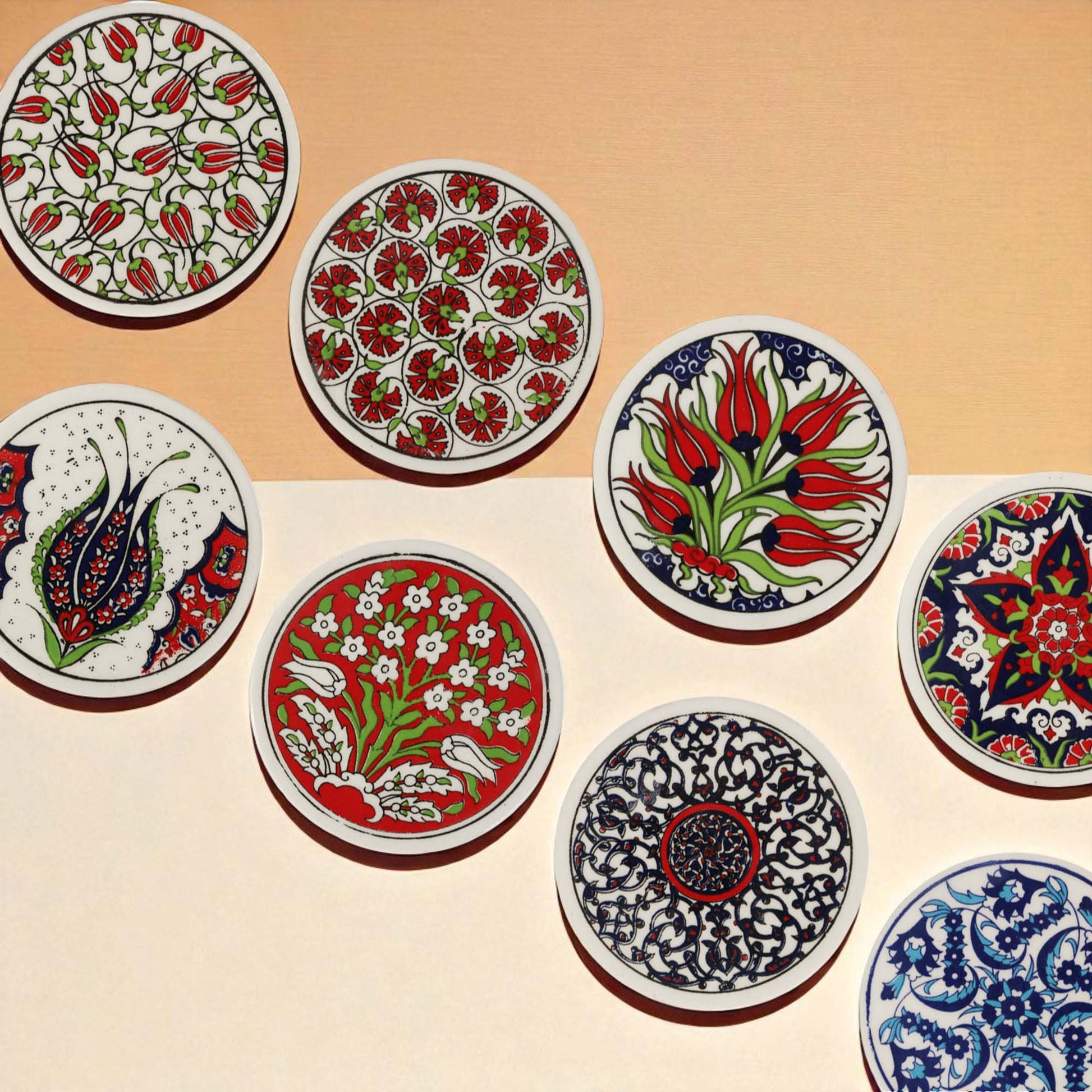 Set of ceramic coasters with intricate floral and geometric designs on a beige background