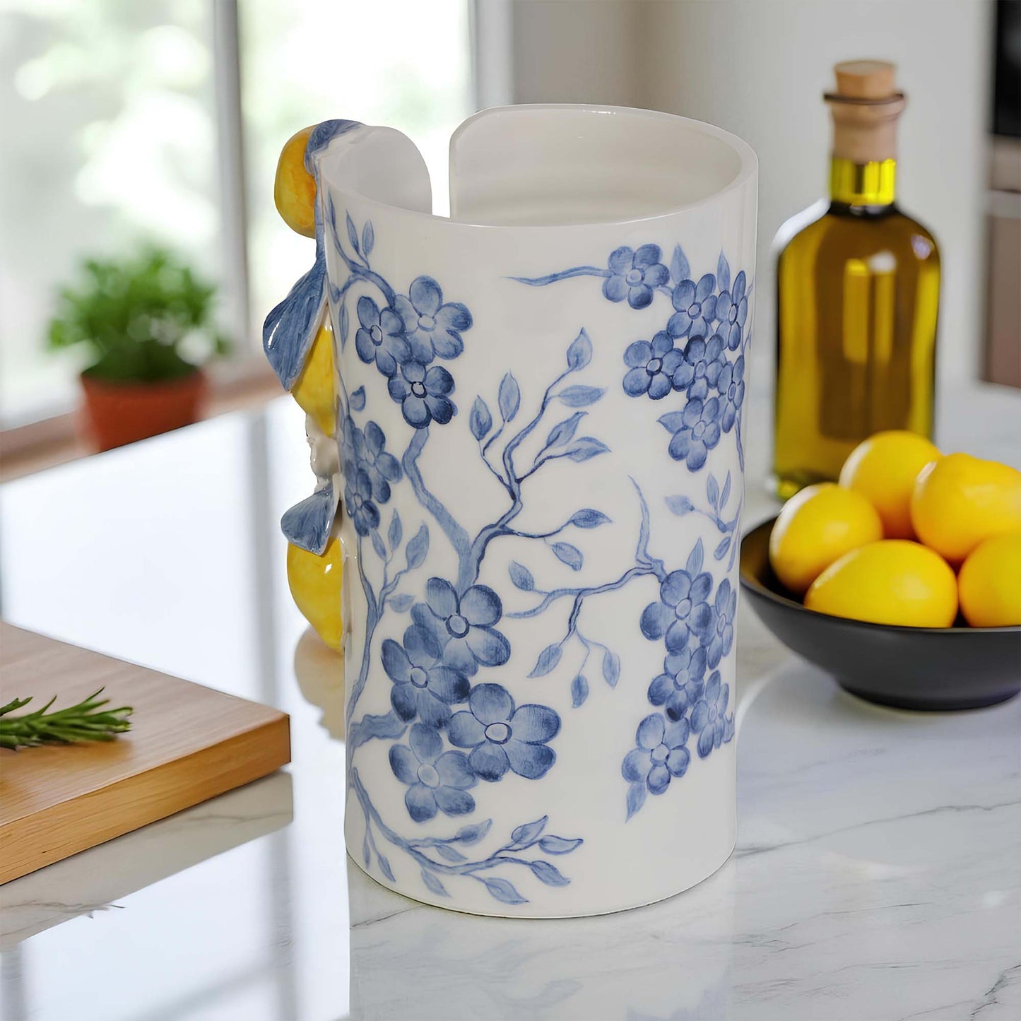 White paper towel holder with blue floral patterns on a kitchen counter with lemons and olive oil.