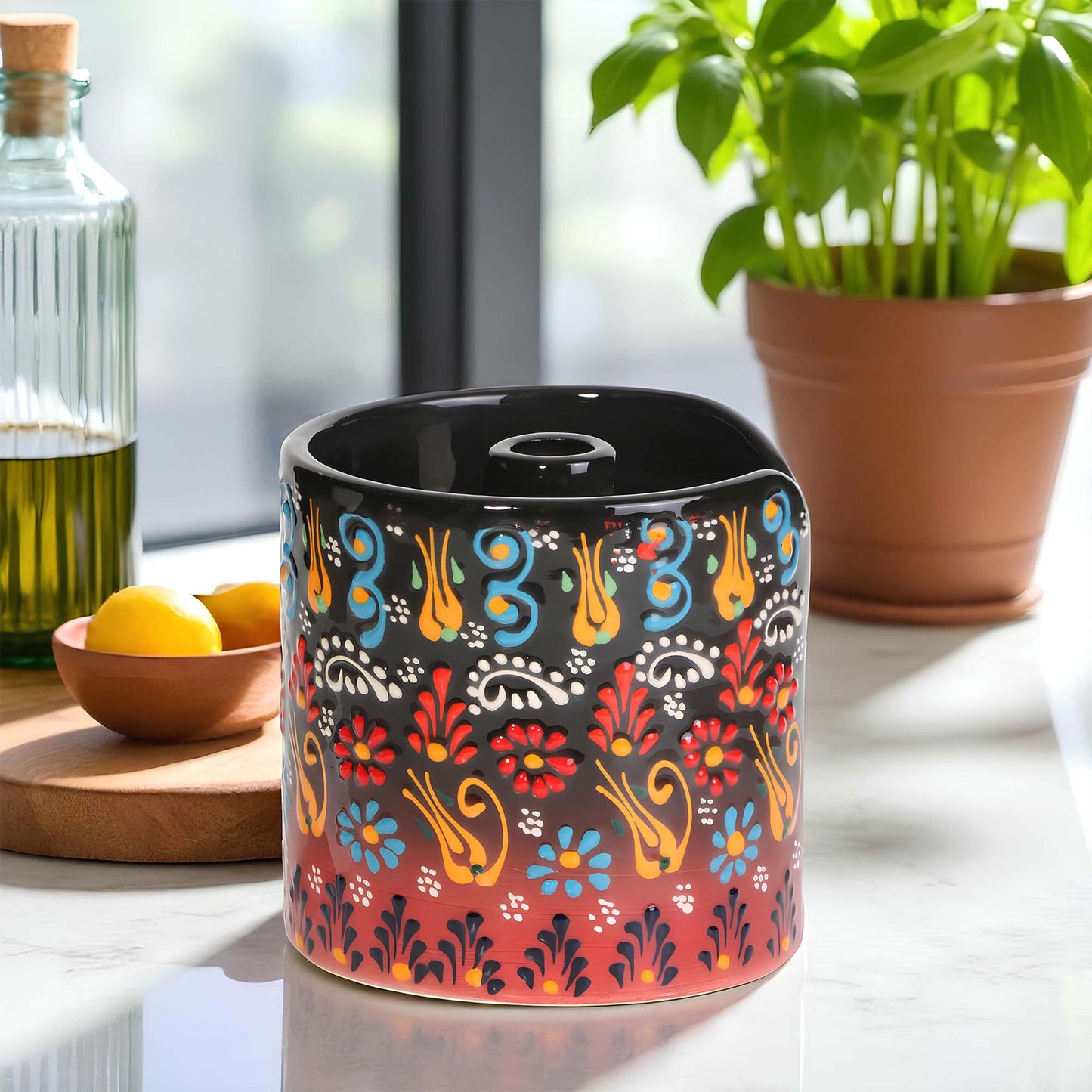 Decorative ceramic paper towel holder with colorful patterns on a table with a plant and bowl in the background.