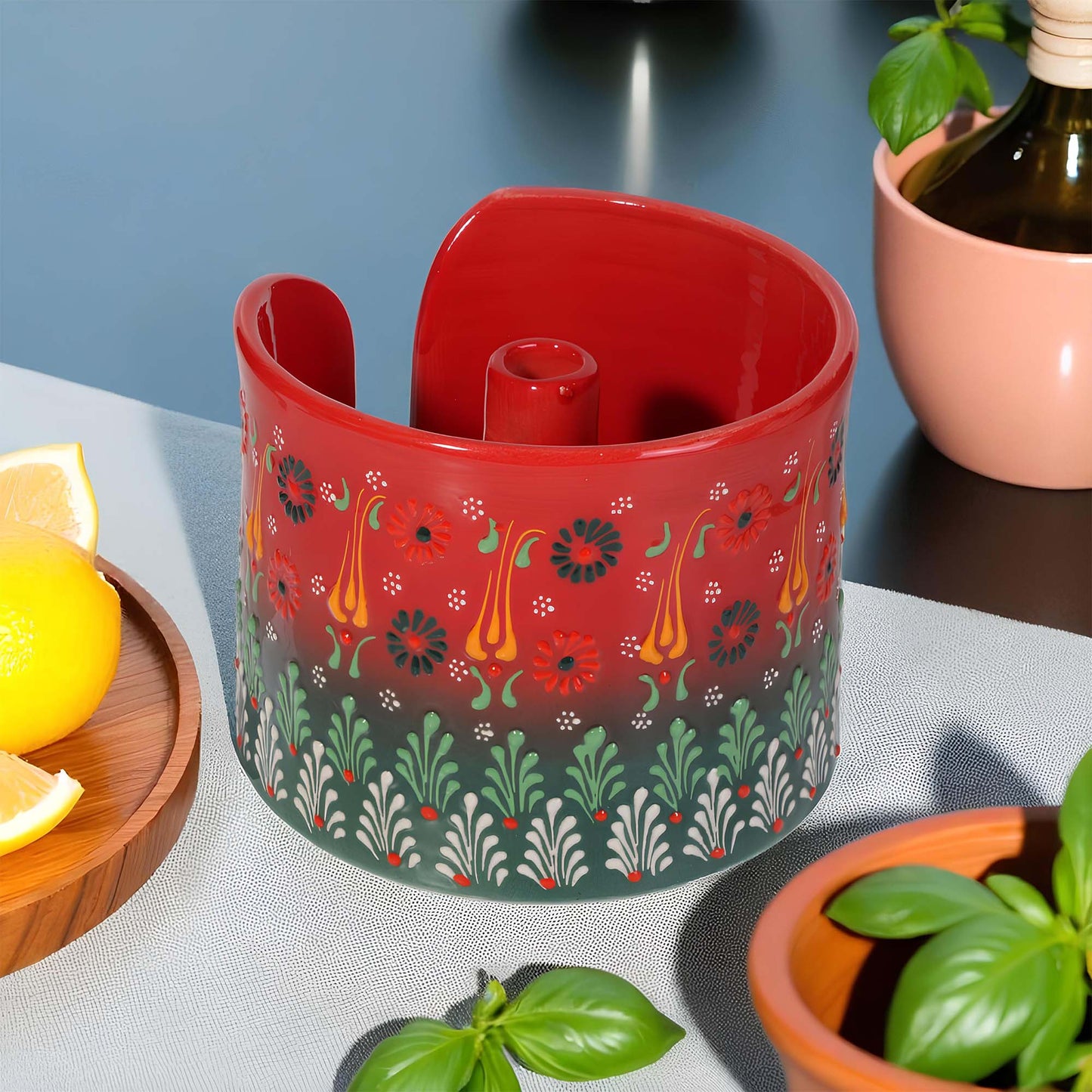 Decorative red paper towel holder with floral pattern on a table with lemons and plants.