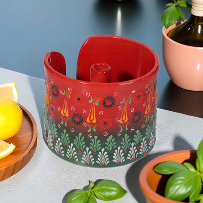 Decorative red paper towel holder with floral pattern on a table with lemons and plants.