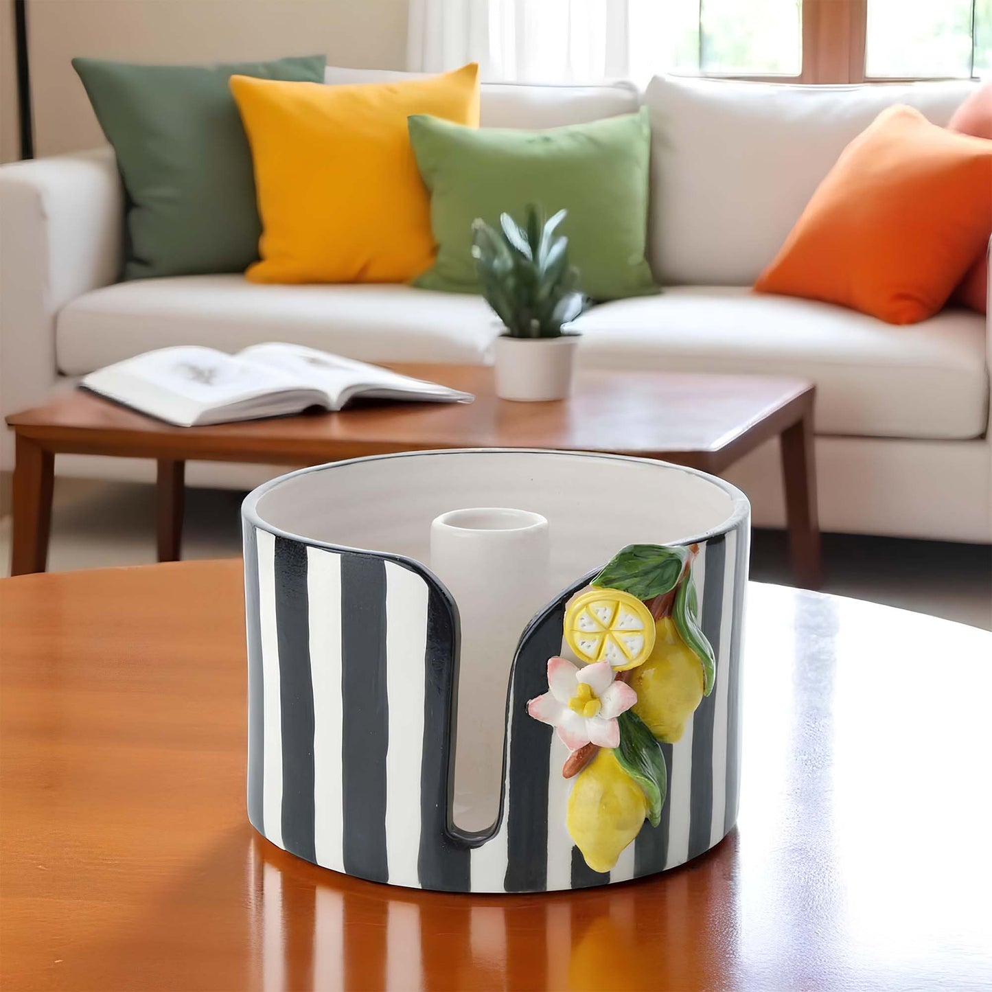 Decorative paper towel holder with lemon and flower design on a wooden table in a living room.