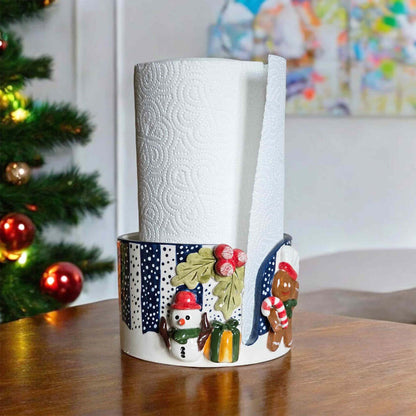 Decorative paper towel holder with Christmas design on a table in front of a decorated tree.