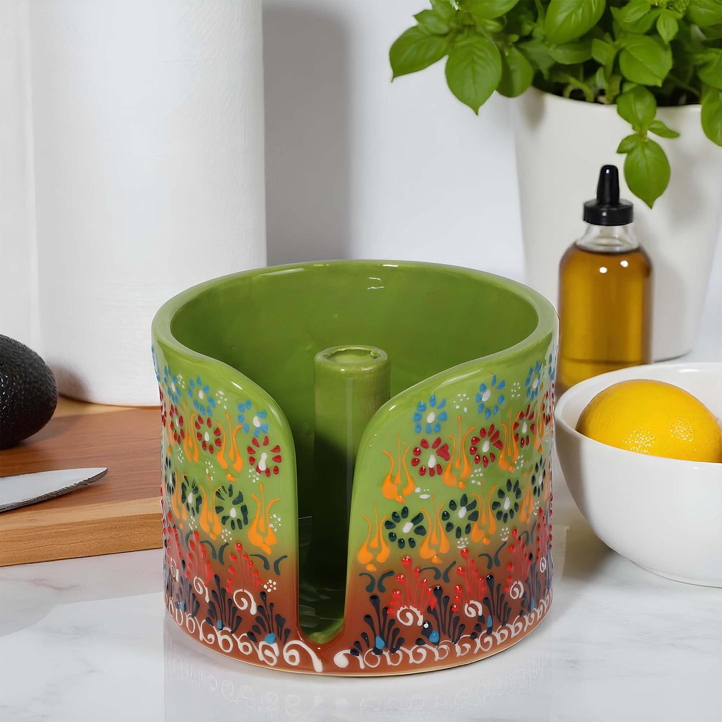 Decorative green paper towel holder with floral patterns on a kitchen counter.