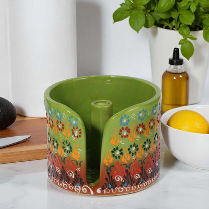 Decorative green paper towel holder with floral patterns on a kitchen counter.