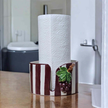 Decorative paper towel holder with grapes design on a wooden surface.