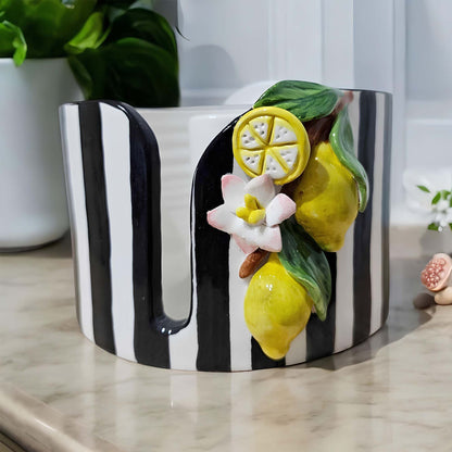 Black and white striped paper towel holder with lemon and flower decorations on a light surface.
