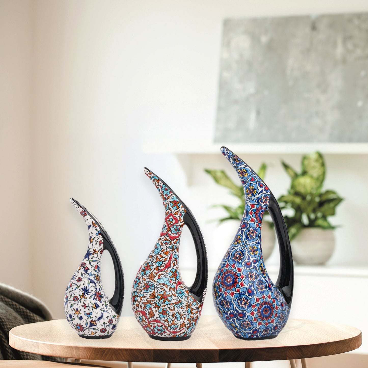 Set of 3 hand-painted ceramic ewers with Ottoman floral motifs in unique color palettes. Glossy artisan pieces with black handles, perfect décor or gifts.