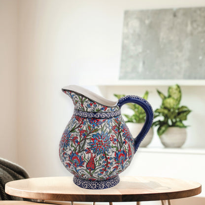 Hand-painted ceramic pitcher with Iznik-inspired tulips, carnations & leaves in red, blue & green. Decorative artisan piece, perfect for display.