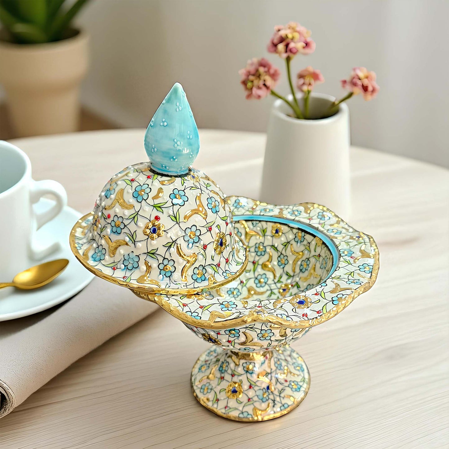 Decorative ceramic sugar bowl with floral patterns on a table with a cup and saucer.