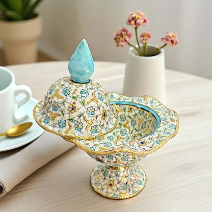 Decorative ceramic sugar bowl with floral patterns on a table with a cup and saucer.