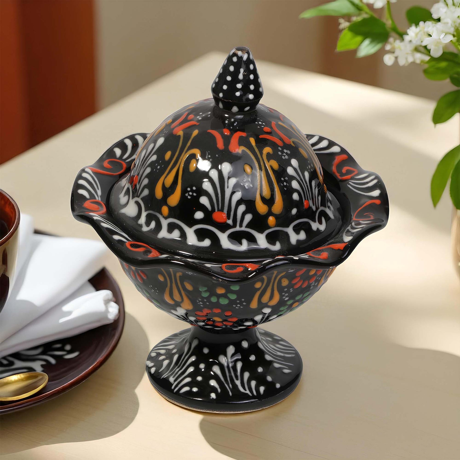 Decorative black ceramic sugar bowl with colorful patterns on a table.