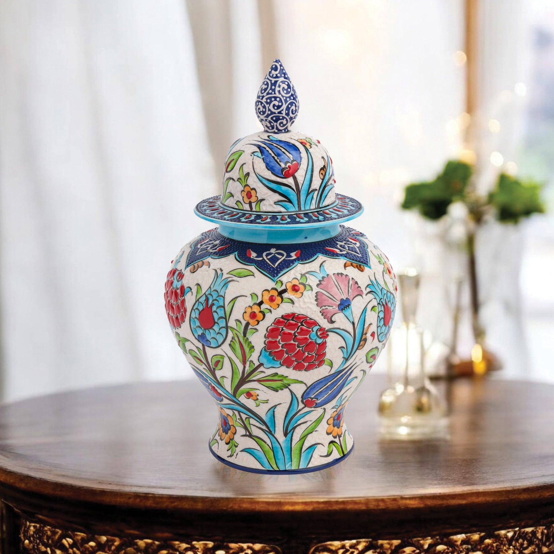 Hand-painted Floral Festival ceramic jar with red carnations, blue tulips & yellow blossoms. Glossy artisan jar with cobalt finial lid, perfect décor or gift.