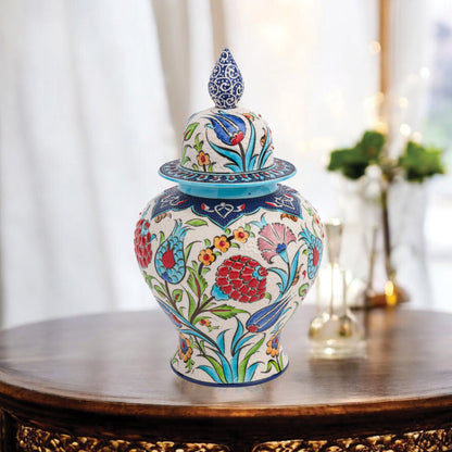 Hand-painted Floral Festival ceramic jar with red carnations, blue tulips & yellow blossoms. Glossy artisan jar with cobalt finial lid, perfect décor or gift.