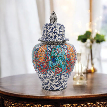Hand-painted Garden Song ceramic jar with floral and bird motifs in vibrant panels. Lidded artisan jar with ornate finial, perfect décor accent or gift.