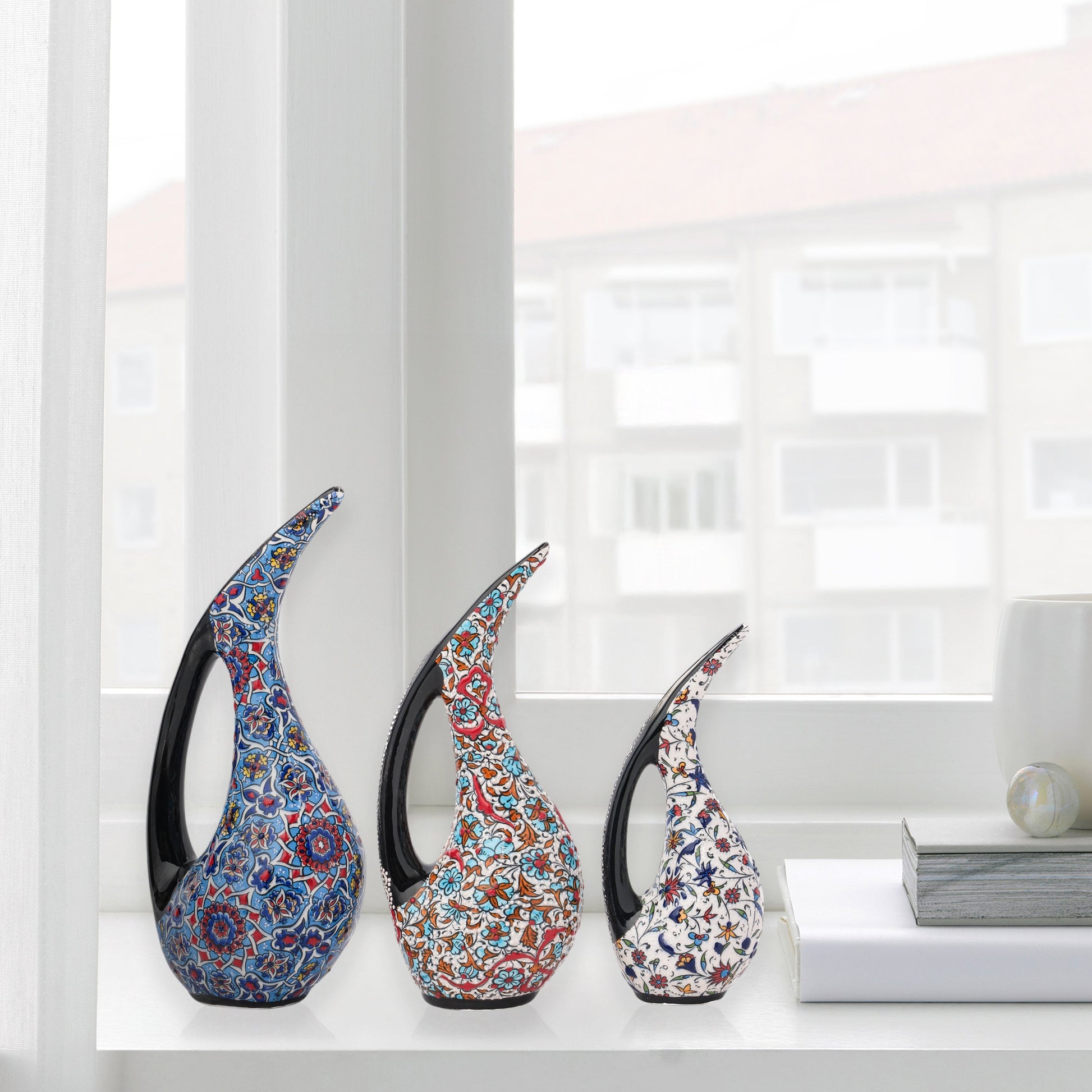 Set of 3 hand-painted ceramic ewers with Ottoman floral motifs in unique color palettes. Glossy artisan pieces with black handles, perfect décor or gifts.