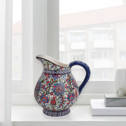 Hand-painted ceramic pitcher with Iznik-inspired tulips, carnations & leaves in red, blue & green. Decorative artisan piece, perfect for display.
