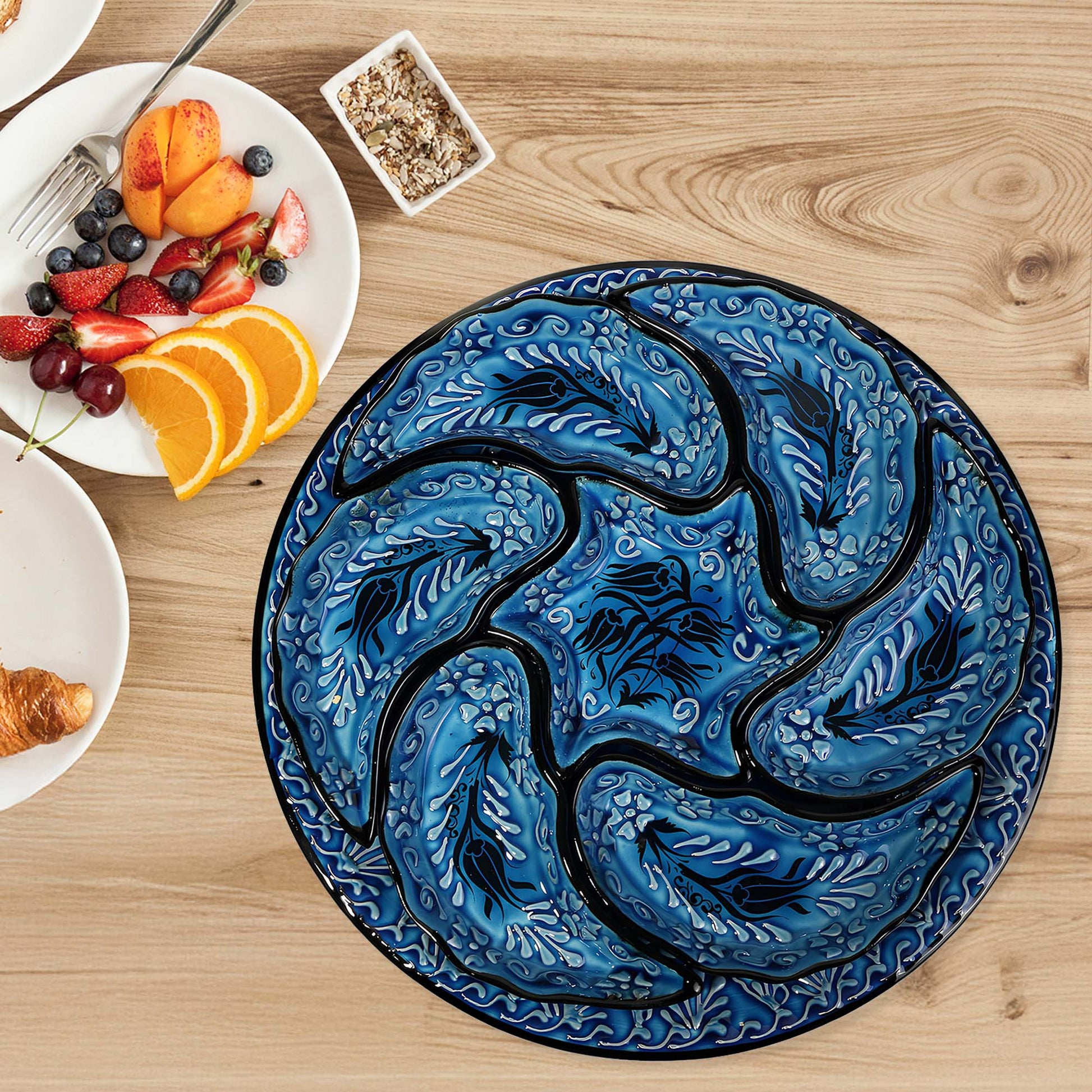 Decorative blue and black snack serving tray set with a tulip design on a wooden table with breakfast items.