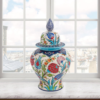 Hand-painted Floral Festival ceramic jar with red carnations, blue tulips & yellow blossoms. Glossy artisan jar with cobalt finial lid, perfect décor or gift.