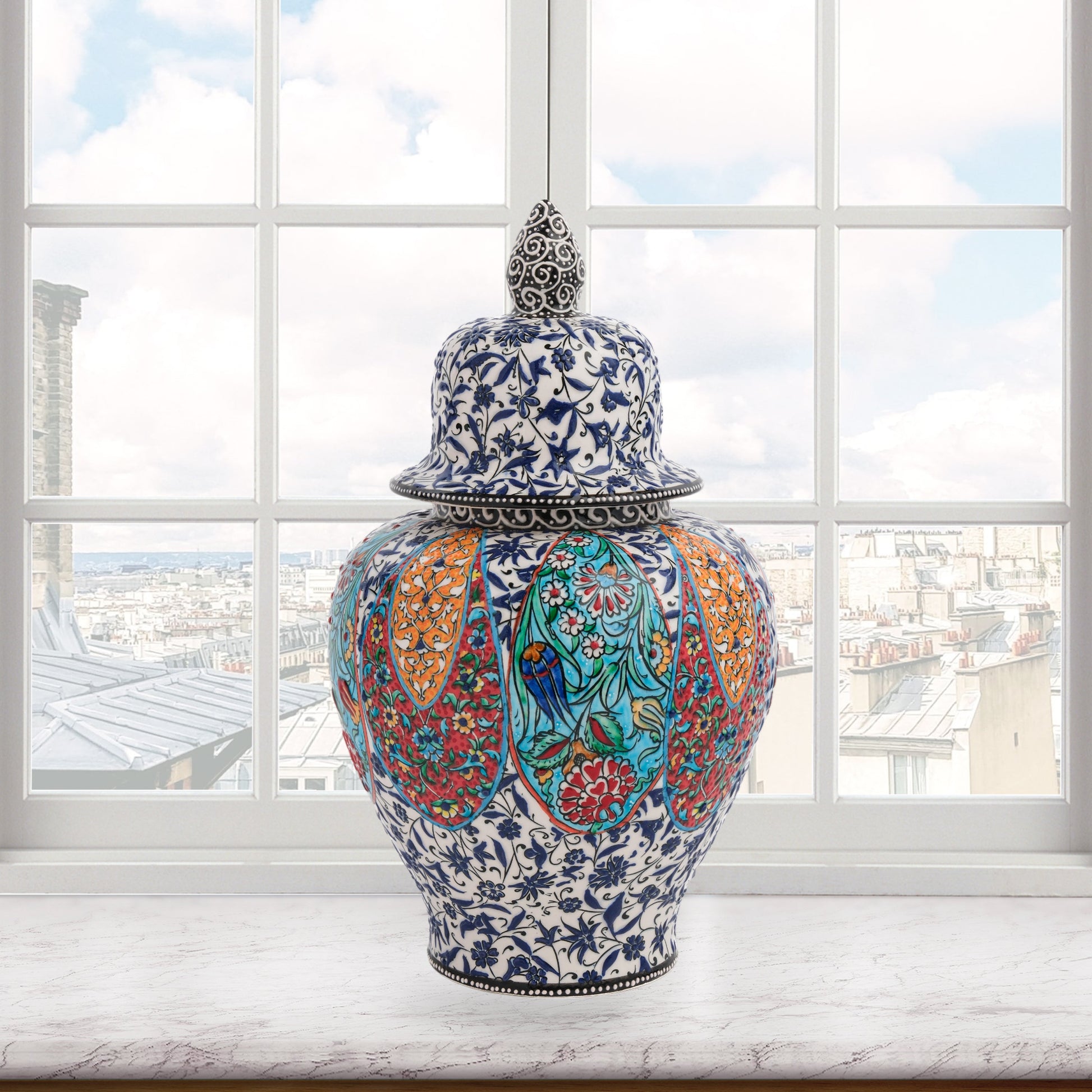 Hand-painted Garden Song ceramic jar with floral and bird motifs in vibrant panels. Lidded artisan jar with ornate finial, perfect décor accent or gift.