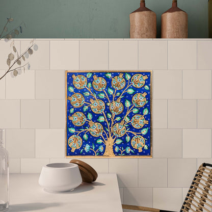 Decorative ceramic tile of a tree with blue background on a tiled wall.