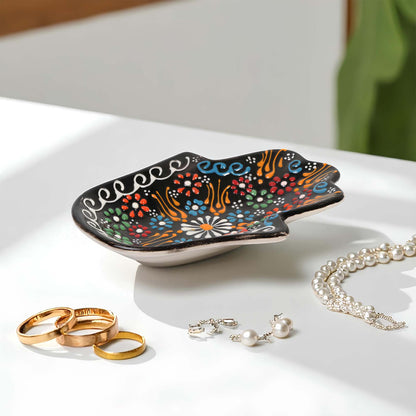 Decorative jewelry tray with colorful patterns on a white surface with jewelry items.